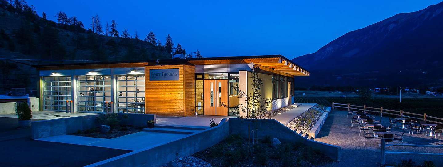 A building illuminated at night, set against a backdrop of mountains under a starry sky.