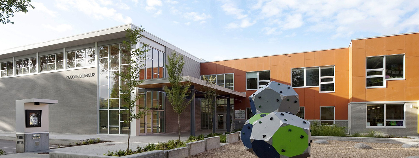 A building stands behind a prominent sculpture displayed in front of it, showcasing art and architecture together.